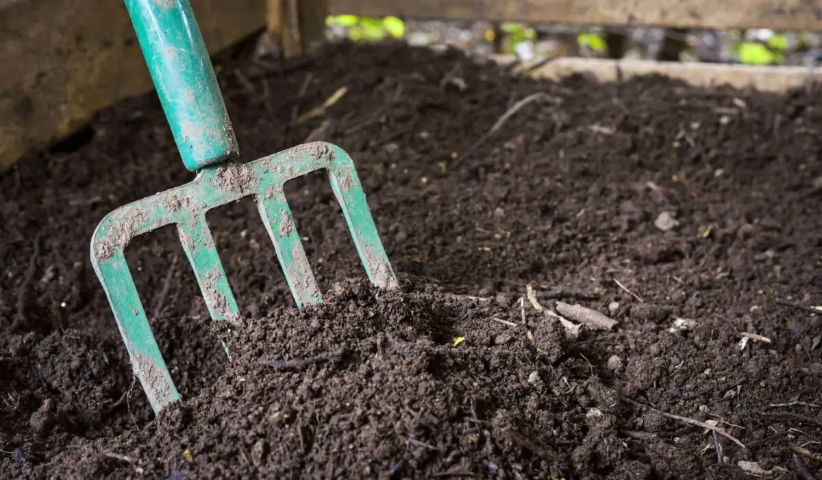 Compost ready to use in a compost bin with a spading fork.